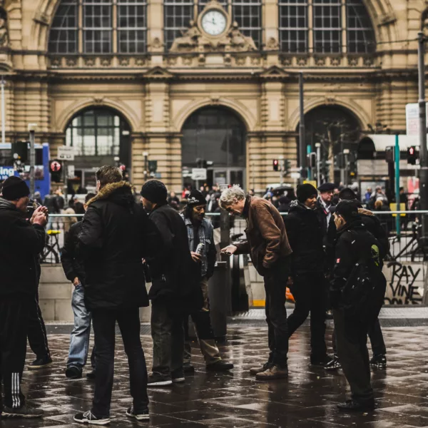 Crowd gathered outside a historic train station in Germany on a rainy day