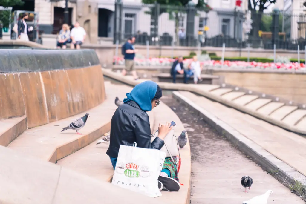 A Muslim woman sitting by a fountain the UK