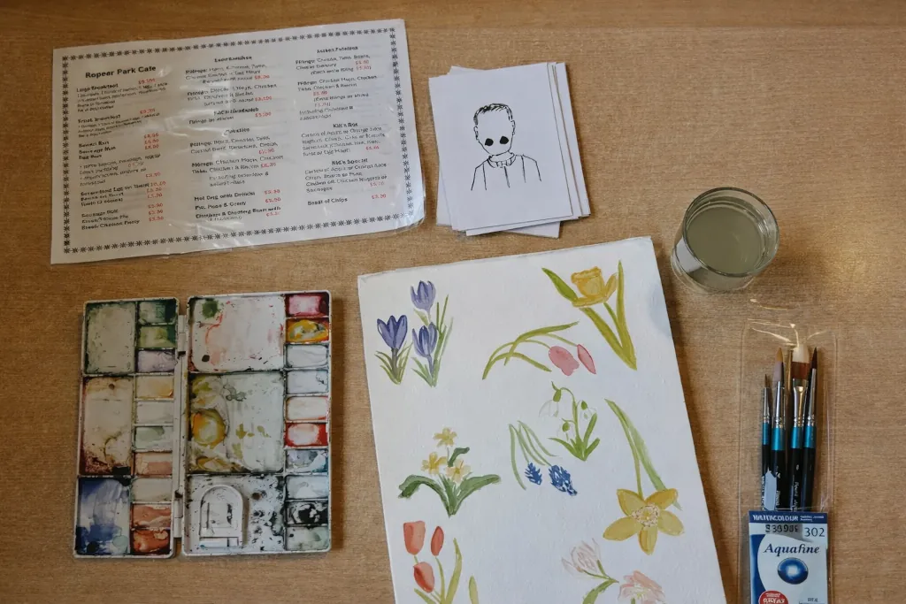 Watercolor painting supplies and floral sketches prepared for creative outreach in a public park