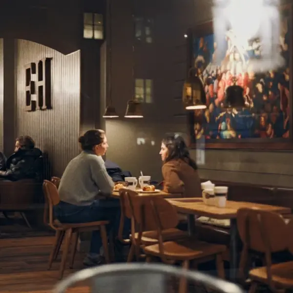 Two people talking over coffee inside a café in Sweden