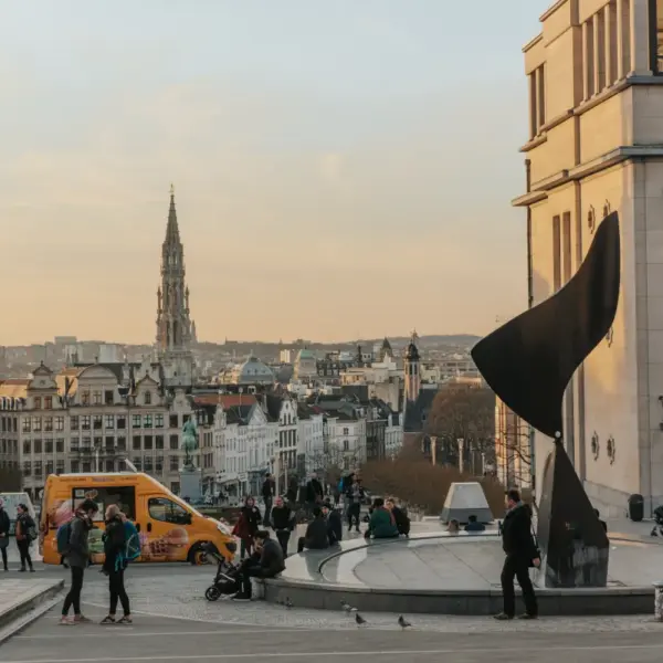 Pedestrians overlooking central Brussels with historic buildings and a church spire in the distance