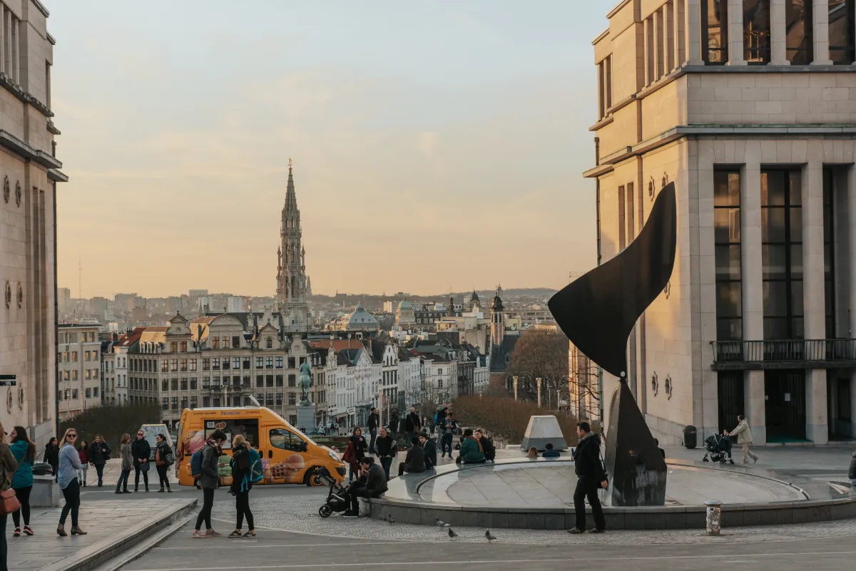 Pedestrians overlooking central Brussels with historic buildings and a church spire in the distance