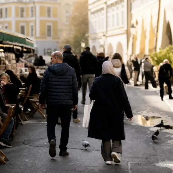 Pedestrians walking through a lively historic street in the Czech Republic with cafés and shops