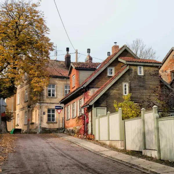 Quiet residential street in Latvia lined with historic wooden houses and autumn trees