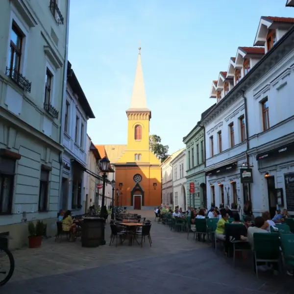 Pedestrian street in Slovakia lined with cafés and historic buildings leading toward a church tower